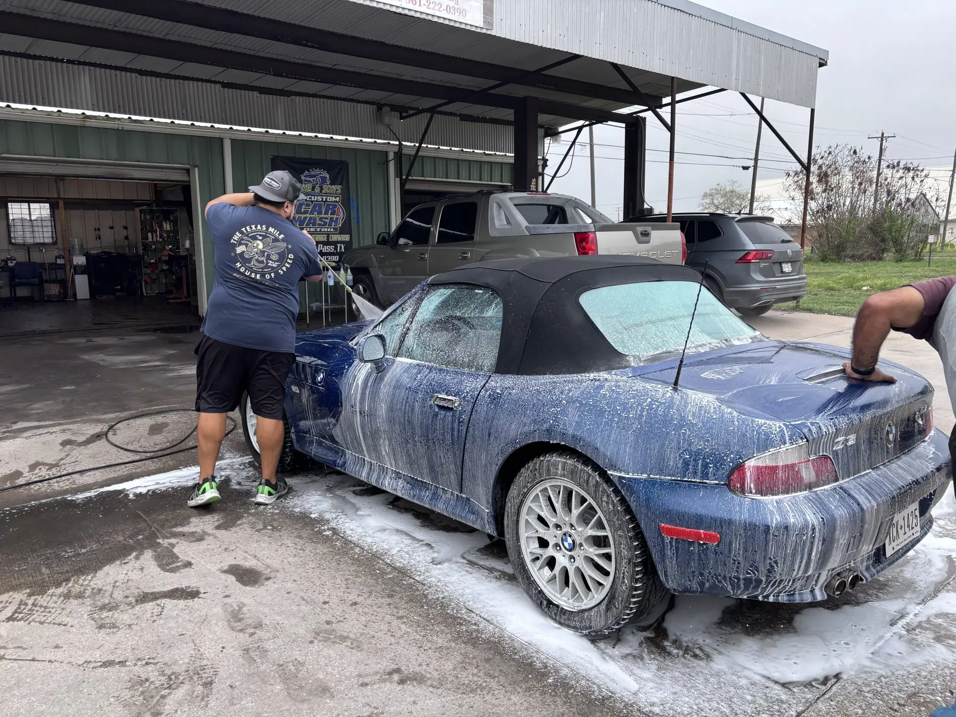 Employee and owner washing a blue BMW convertible