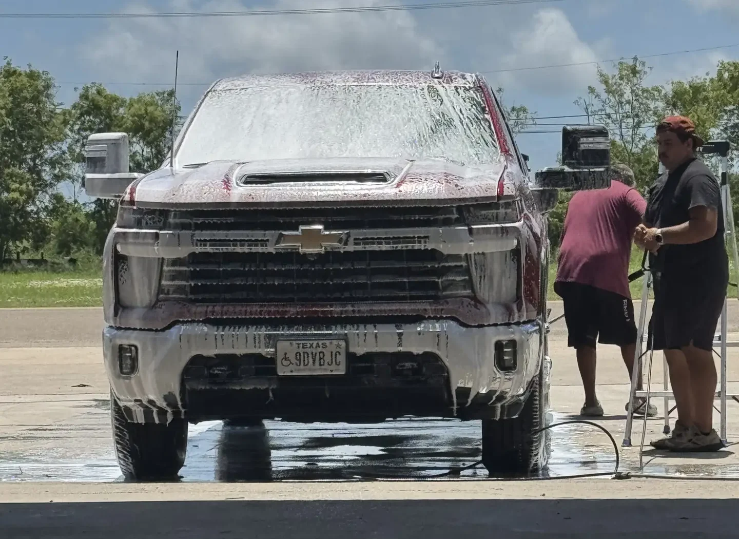 Two employees work on washing a full size Chevy truck